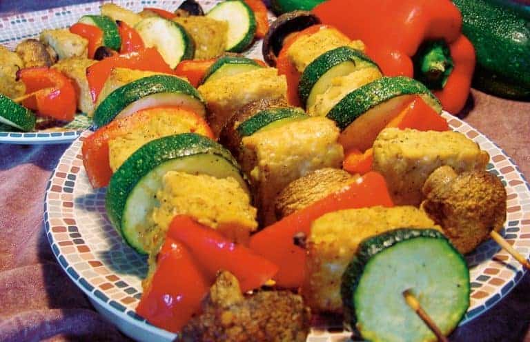 Tempeh and vegetable kabobs with onions peppers zucchini and mushrooms