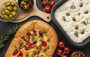 Focaccia bread studded with rosemary, tomatoes and olives, and garnished with fresh tomatoes