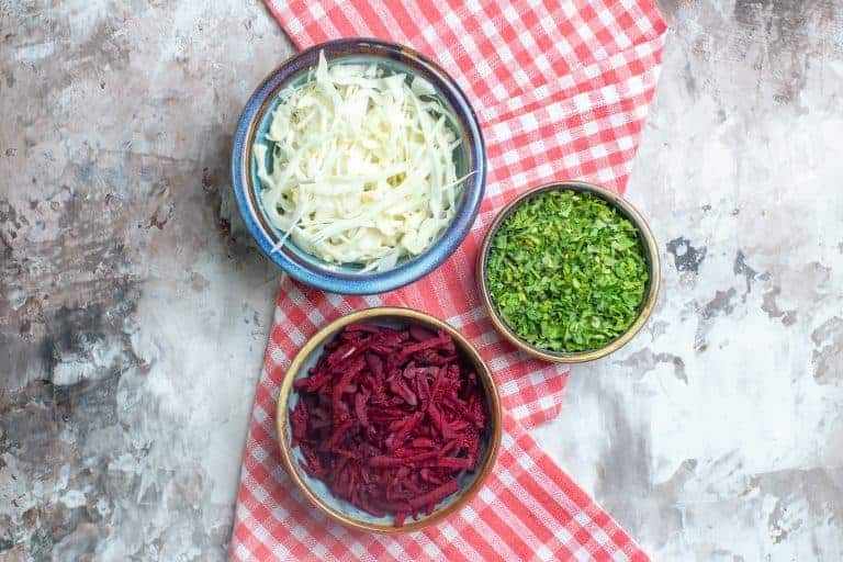 Chopped cabbage, grated beets and greens, in bowls and ready to serve