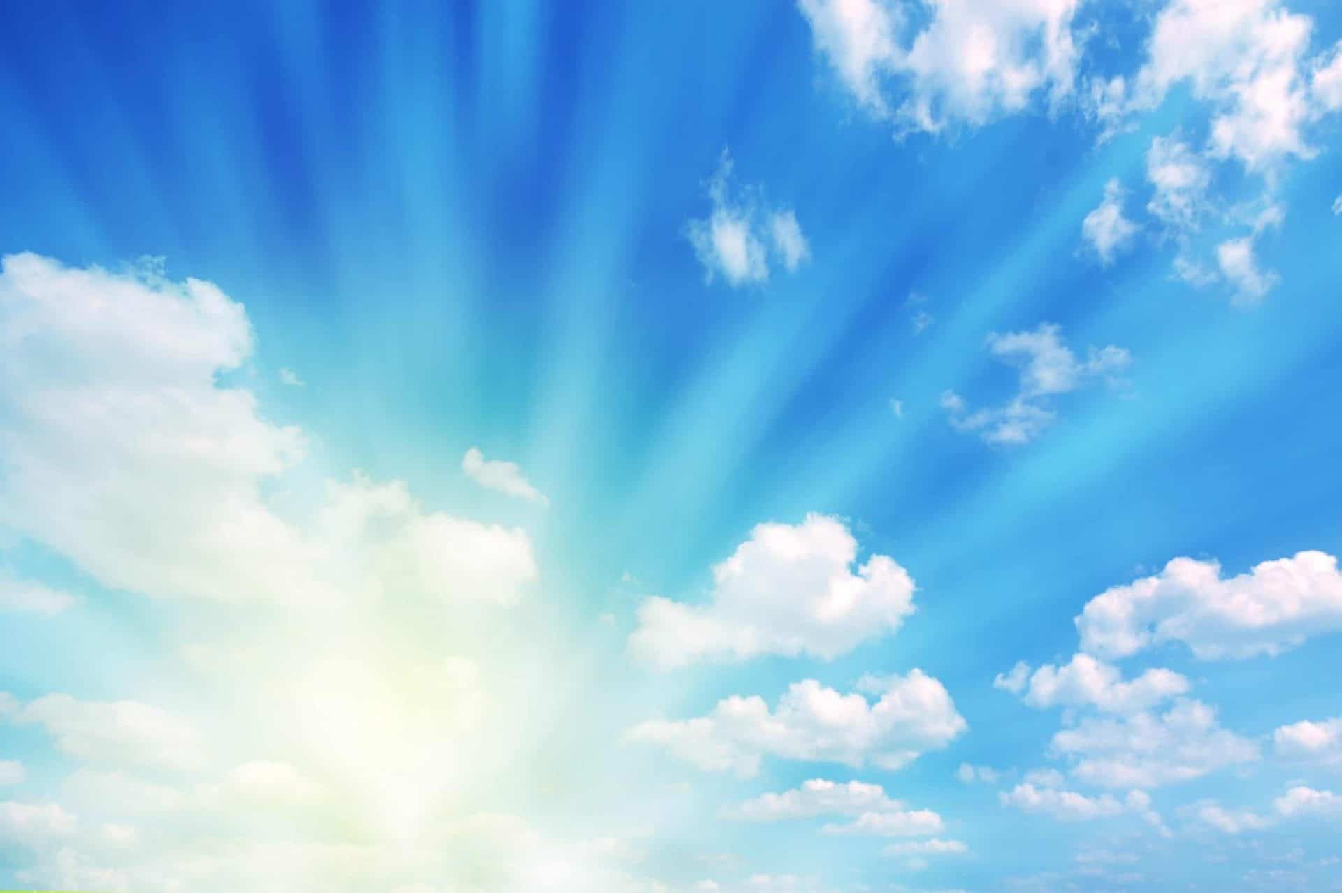 Blue sky filled with puffy clouds and sun rays