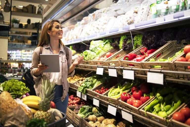 Woman with tablet buying produce in a grocery store