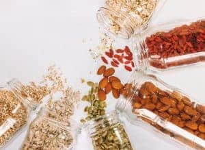 Six glass jars with different colored bulk foods spilling out
