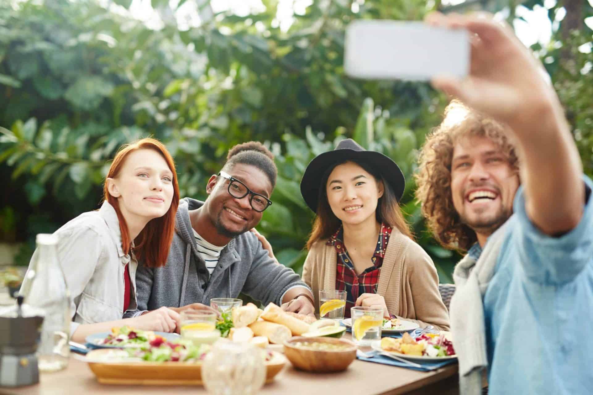 Becoming Vegan, Group of smiling friends taking selfie at outdoor dining table